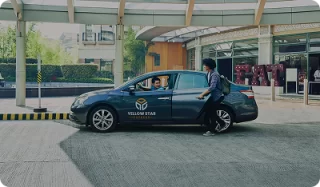 Passenger approaching a Yellow Star Express Taxi sedan outside a building